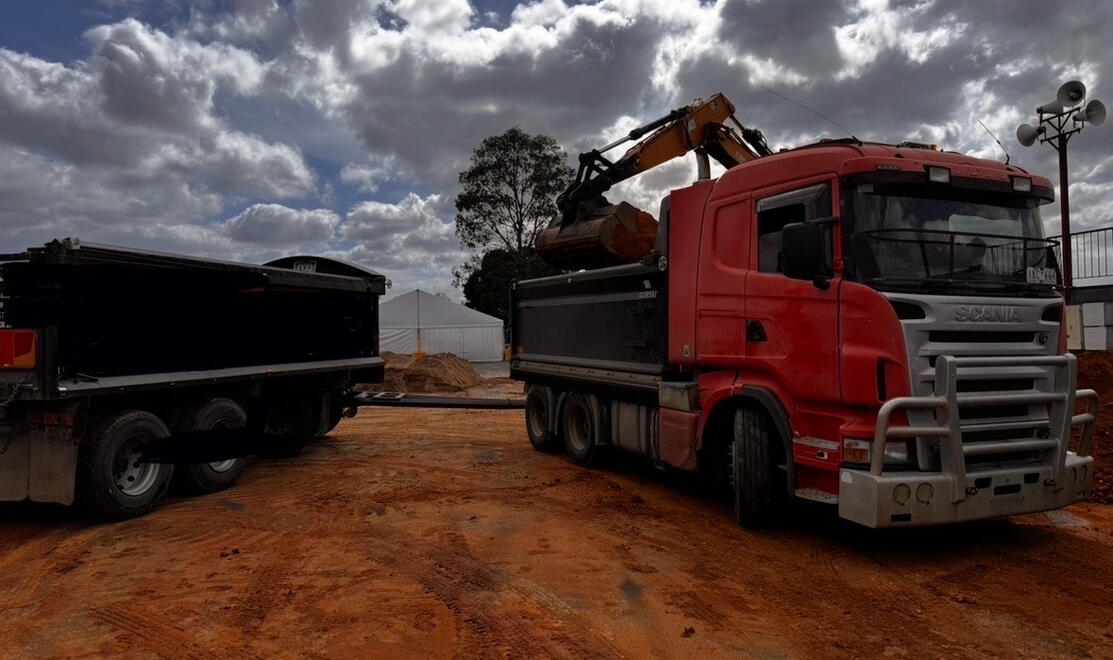 Tipper Truck on Worksite Melbourne – All Equipped Plant Hire Red tipper truck unloading soil on a construction site in Melbourne
