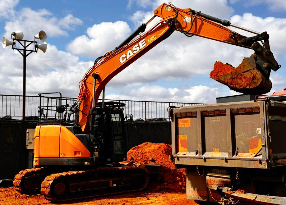 Case Excavator Moving Soil – All Equipped Plant Hire Case excavator tipping bright orange soil into a trailer.